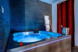 Loft Romantique - Spa Privatif - Spa Noctambulles في هييريس: حوض استحمام أزرق في حمام مع ستارة حمراء