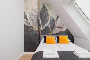 a bedroom with a bed with orange and black pillows at Prestige Apartments 12 in Wrocław