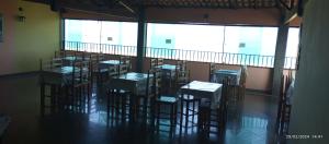 a group of tables and chairs in a room with large windows at Pousada praia do riacho in Guarapari