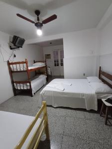 a bedroom with two beds and a ceiling fan at Pousada praia do riacho in Guarapari