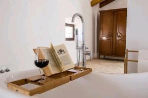 una copa de vino y un libro sobre una bañera en La Aceitera, en Bollullos de la Mitación