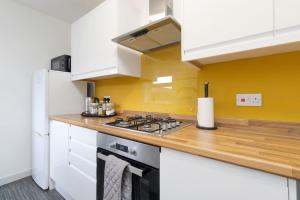 cocina con fogones y pared amarilla en Spacious 4 Bed house W/Free Parking Sleeps 7 Near Walsgrave Hospital en Wyken