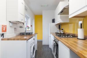 cocina con armarios blancos y encimera de madera en Spacious 4 Bed house W/Free Parking Sleeps 7 Near Walsgrave Hospital en Wyken