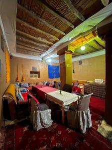 Camp Mbark authentic في Mhamid: غرفة مع طاولة وكراسي وأريكة