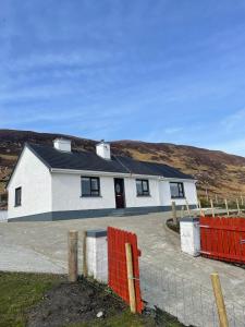 een wit huis met een hek ervoor bij Eileen’s Cottage in Donegal