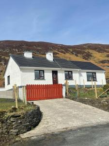 een wit huis met een rood hek ervoor bij Eileen’s Cottage in Donegal