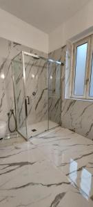 a marble bathroom with a shower and a window at Room Rental in Naples
