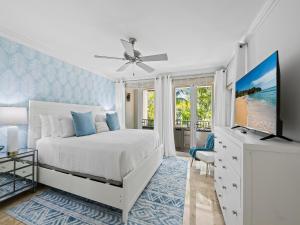 a white bedroom with a bed and a television at Walk to Las Olas Heated Splash Pool Jacuzzi in Fort Lauderdale