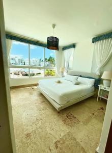 ein Schlafzimmer mit einem großen Bett und einem großen Fenster in der Unterkunft Gourgeous 2 bedroom Beach Apt Playa Nueva Romana in San Pedro de Macorís