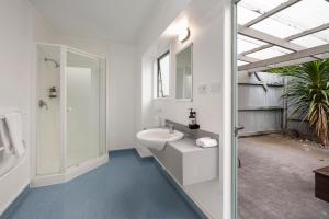 uma casa de banho branca com um lavatório e um chuveiro em Fenton Court Motel em Rotorua