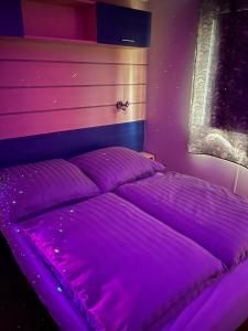 Bett in einem Zimmer mit violetter Beleuchtung in der Unterkunft *Air-conditioned* Mobilhome near Europapark in Boofzheim