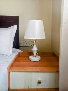 a lamp on a wooden table next to a bed at Lovely Double Bed with a Private Garden Nook in Kira