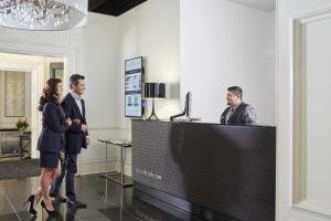 a group of people standing around a reception desk at The Queens Gate Hotel in London