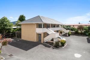 a house with a staircase in a parking lot at Fenton Court Motel in Rotorua