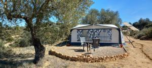 ein blau-weißes Zelt mit einem Tisch und Stühlen in der Unterkunft Caravan Finca La Vida Rustica in Maella