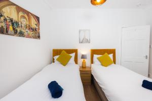 two beds in a room with white walls and yellow pillows at Warm&Welcoming City Centre Apartments by Meadows 6 in Edinburgh