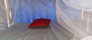een rood kussen bovenop een wit bed bij La casa mono cuco Hostel in San Antero