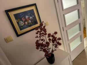 un vase de fleurs sur une table à côté d'un tableau dans l'établissement Mirror Apartment, à Novi Pazar
