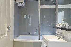 a bathroom with a shower and a tub and a sink at The Queens Gate Hotel in London