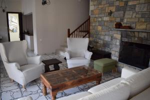 a living room with white chairs and a fireplace at Serenity Agia Eleni Vacation House in Koukounaries