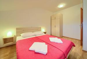 um quarto com uma cama vermelha com duas toalhas em Nette Wohnung in Šilo mit Möblierter Terrasse em Šilo