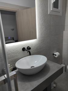 bagno con lavandino bianco e specchio di Vythos ad Adámas