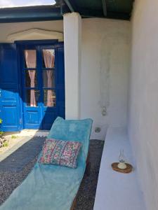 un sofá con una almohada en una habitación con puertas azules en Arancio independent room in Ecovilla on the beach en Apolakkiá