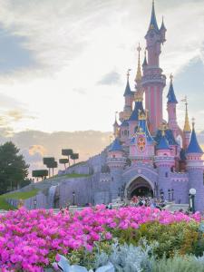 un castillo de Disney con flores rosas delante de él en The Green Terrace Disneyland en Chessy