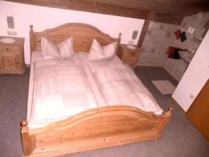 uma cama de madeira com lençóis brancos e almofadas na casa de banho em Dachgeschosswohnung mit toller Aussicht vom Balkon auf den wenige Meter entfernten See em Bayersoien