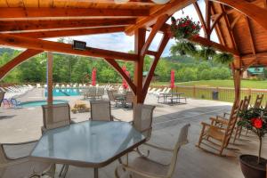 eine Terrasse mit einem Tisch, Stühlen und einem Pool in der Unterkunft Bears Valley Inn - Less than 15 Min to Attractions - Great Mtn Views - Private Pool Club - EZ Access Roads - Luv Dogs! in Sevierville