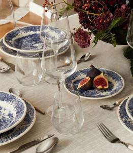 B&B Il Mulino في Osteria di Novoli: طاولة مع الأطباق الزرقاء والأبيض وكؤوس النبيذ