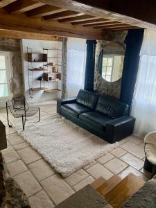 ein Wohnzimmer mit einem schwarzen Sofa und einem Teppich in der Unterkunft gite seccotine in Saint-Mard-de-Vaux