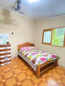 a bedroom with a bed and a dresser and a window at Garden Hostel Tingo María in Tingo María