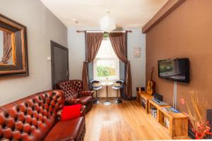 a living room with a leather couch and a television at Warm, Cozy&Relaxed Apartment by Holyrood Palace in Edinburgh