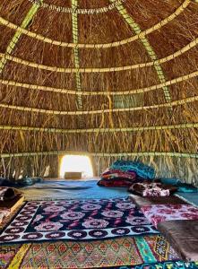 Cama en una cabaña de paja con almohadas y alfombra en Camping-Auberge Odette du Puigaudeau et Aziza en Atar