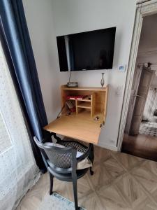 Elle comprend un bureau avec une chaise et une télévision murale. dans l'établissement L'Annexe de MaLou, à Maisons-Laffitte