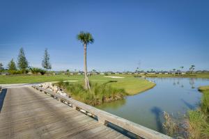 a wooden boardwalk with a palm tree and a pond at Renovated Home in The Villages with Lanai, Golf Cart in The Villages