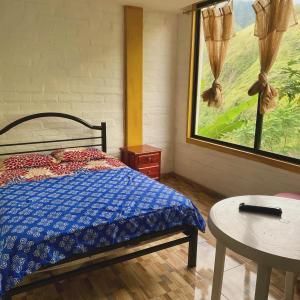 Schlafzimmer mit einem Bett, einem Tisch und einem Fenster in der Unterkunft HOSTERIA SAN GERONIMO in Ibarra