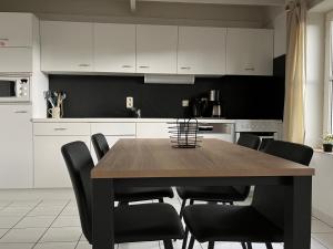 cocina con mesa de madera y sillas negras en Zeebos 112, en Bredene