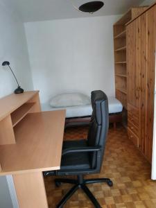 uma secretária e uma cadeira num quarto com uma cama em Spacious Condo, Green Serenity em Palaiseau