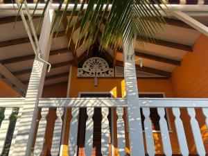 a porch with a white railing and a clock on a house at L'escale Tropicale in Sainte-Anne