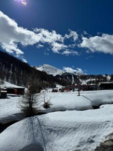 a field covered in snow with mountains in the background at Sestriere Borgata appartamento in montagna Casa di Bertu in Borgata Sestriere
