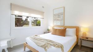 a white bedroom with a bed and a window at Bungalow 21 in Callala Beach