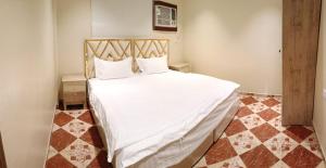 1 dormitorio con cama blanca y cabecero de madera en فندق وسط البلد en Riad