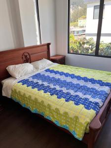 1 dormitorio con 1 cama con manta azul y amarilla en Casa excelente (Llano Chico), en Quito