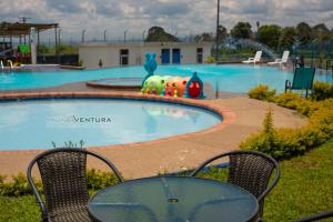 een tafel en stoelen voor het zwembad bij Apartamento Faunaventura cerca Parque del Café con piscina in Montenegro