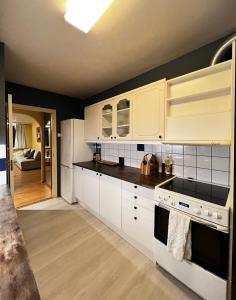 a kitchen with white cabinets and black counter tops at Luxury Service Apartment by Chanya in Ålesund