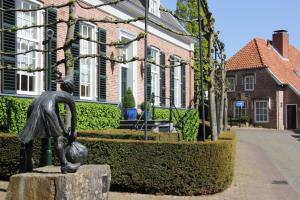 Una statua di una ragazza su un ceppo di fronte a una casa di Hotel Van der Maas a Ootmarsum