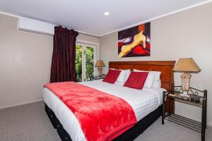 a bedroom with a large bed with a red blanket at Sanctuary Palms in Paihia