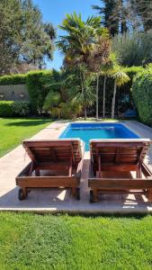 2 bancos de madera situados junto a una piscina en Chacras de Coria Relax en Luján de Cuyo